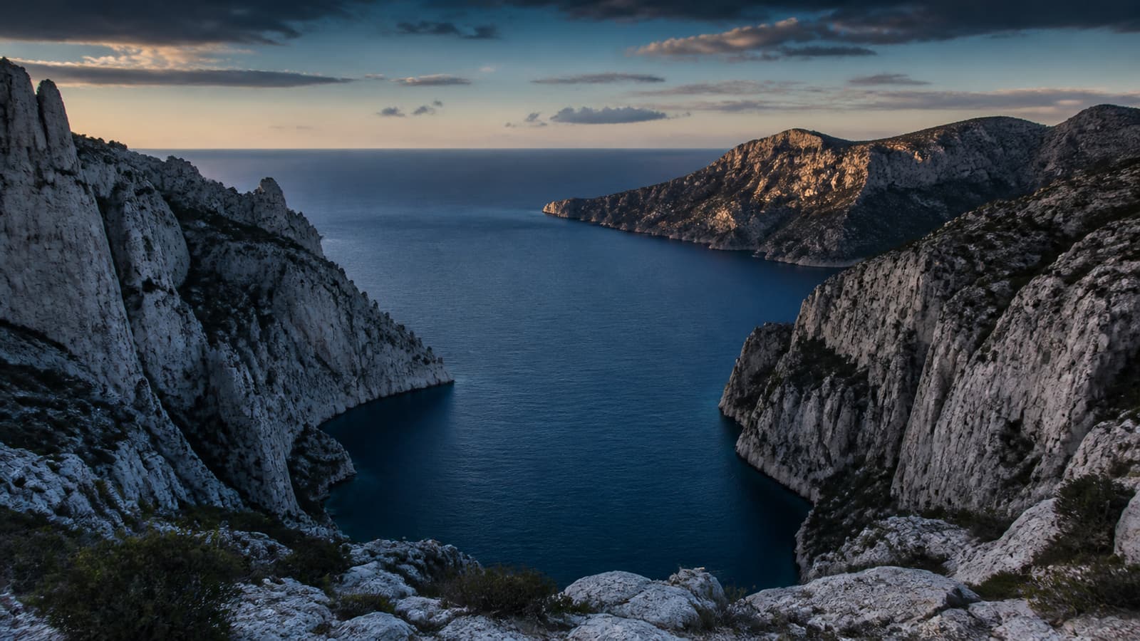 Les falaises calcaires des Calanques entourant une profonde crique méditerranéenne au soleil couchant